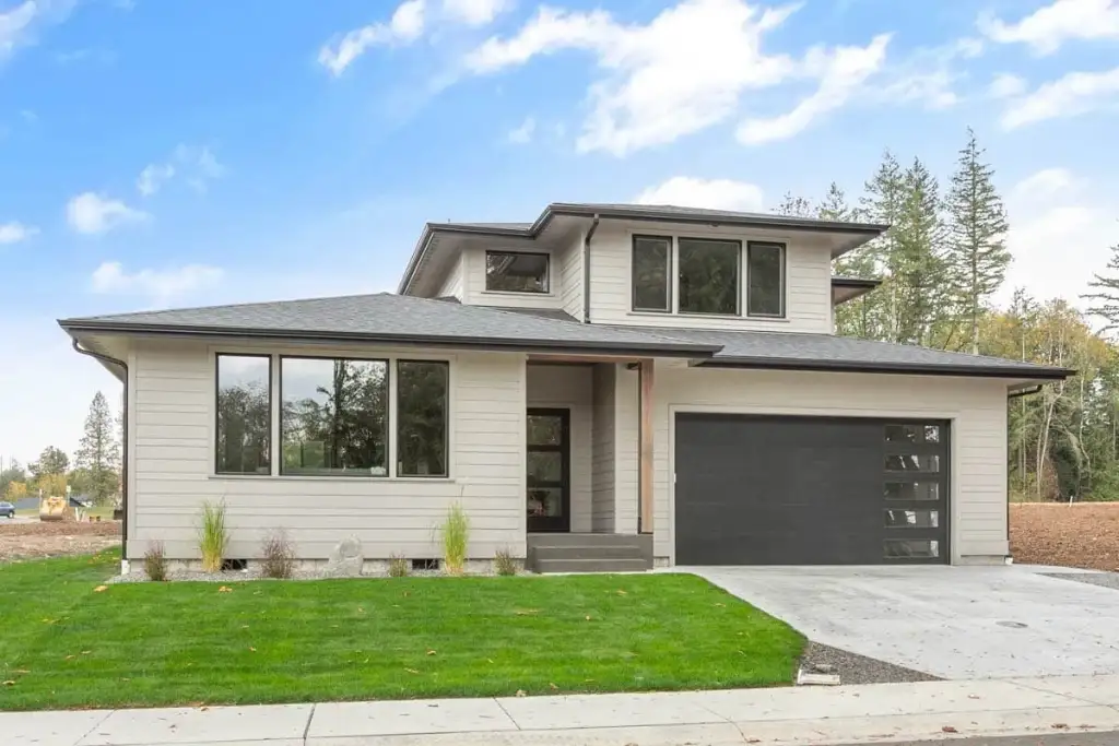 Front elevation of Northwest Modern plan 280263JWD with greige lap siding, low-pitch hip roofs, a cedar-wrapped entry column and a dark two-car garage door