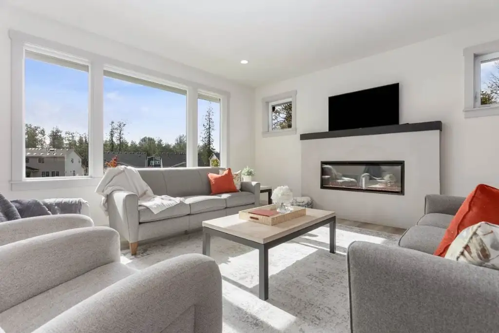 Living room in plan 280263JWD with a linear gas fireplace, dark mantel shelf, mounted television and a bank of windows