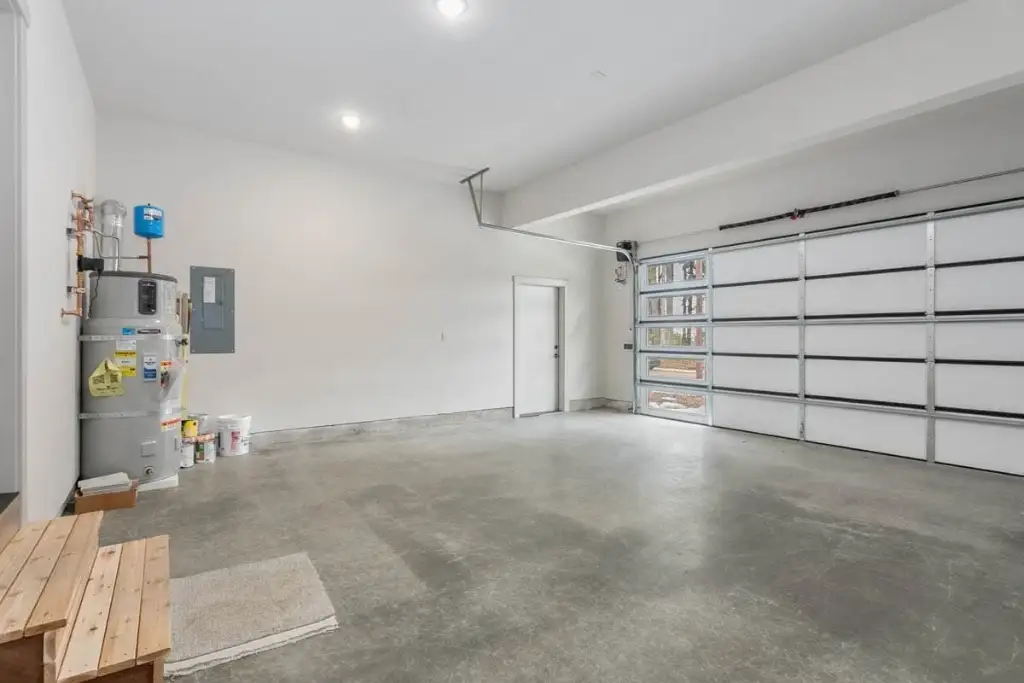 Interior of the 487 sq ft two-car garage in plan 280263JWD with a sectional door, a service door to the house and the water heater and panel on the side wall