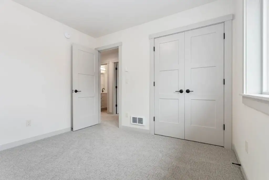Upstairs bedroom in plan 280263JWD with double closet doors, carpet and an open door to the shared hall bathroom