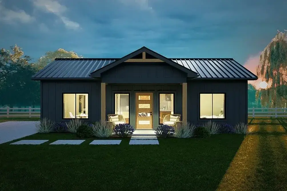 Front exterior of the modern cottage with white shingle siding, black standing seam roof, and covered front porch